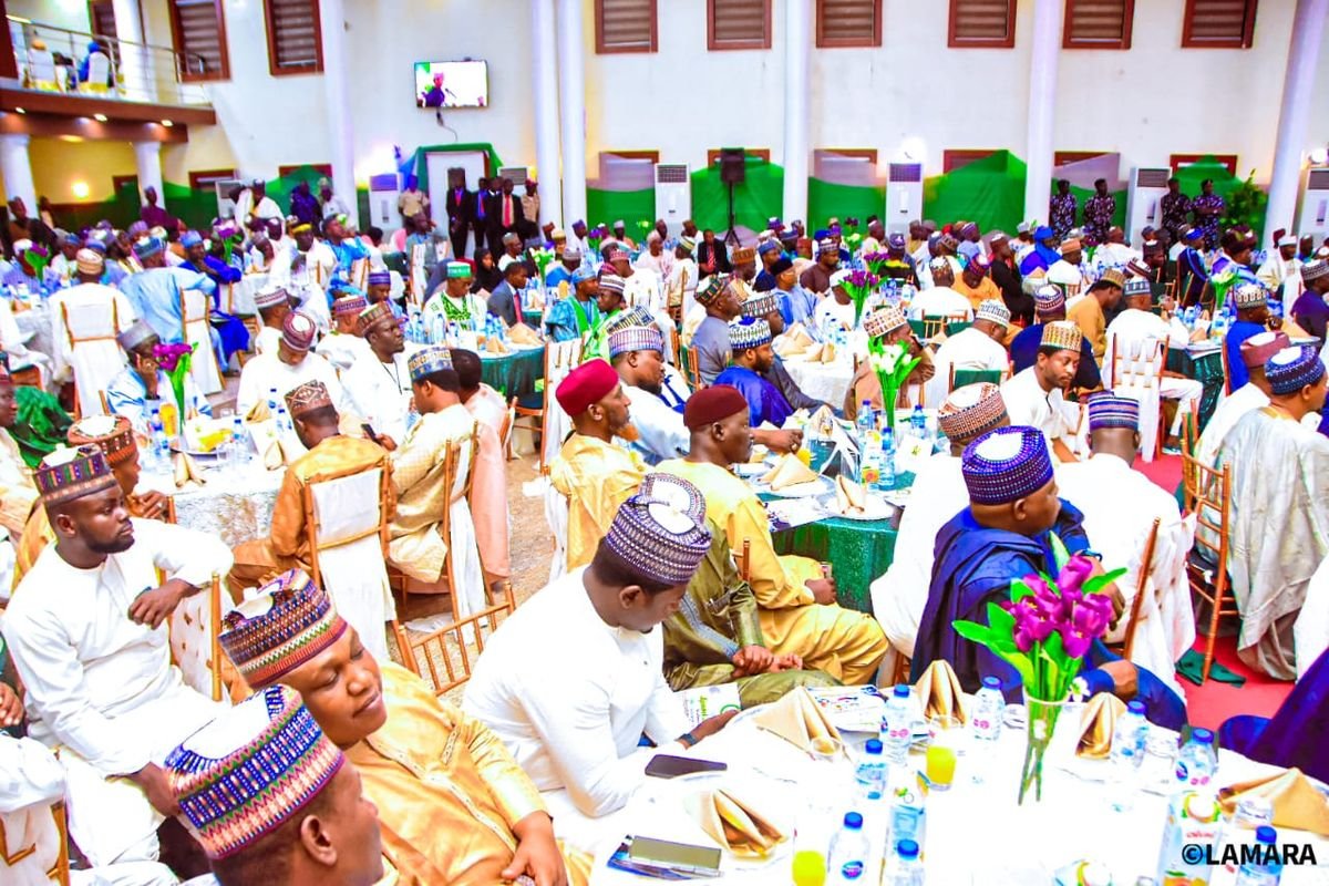 Guests seated at decorated tables during a large event in a hall